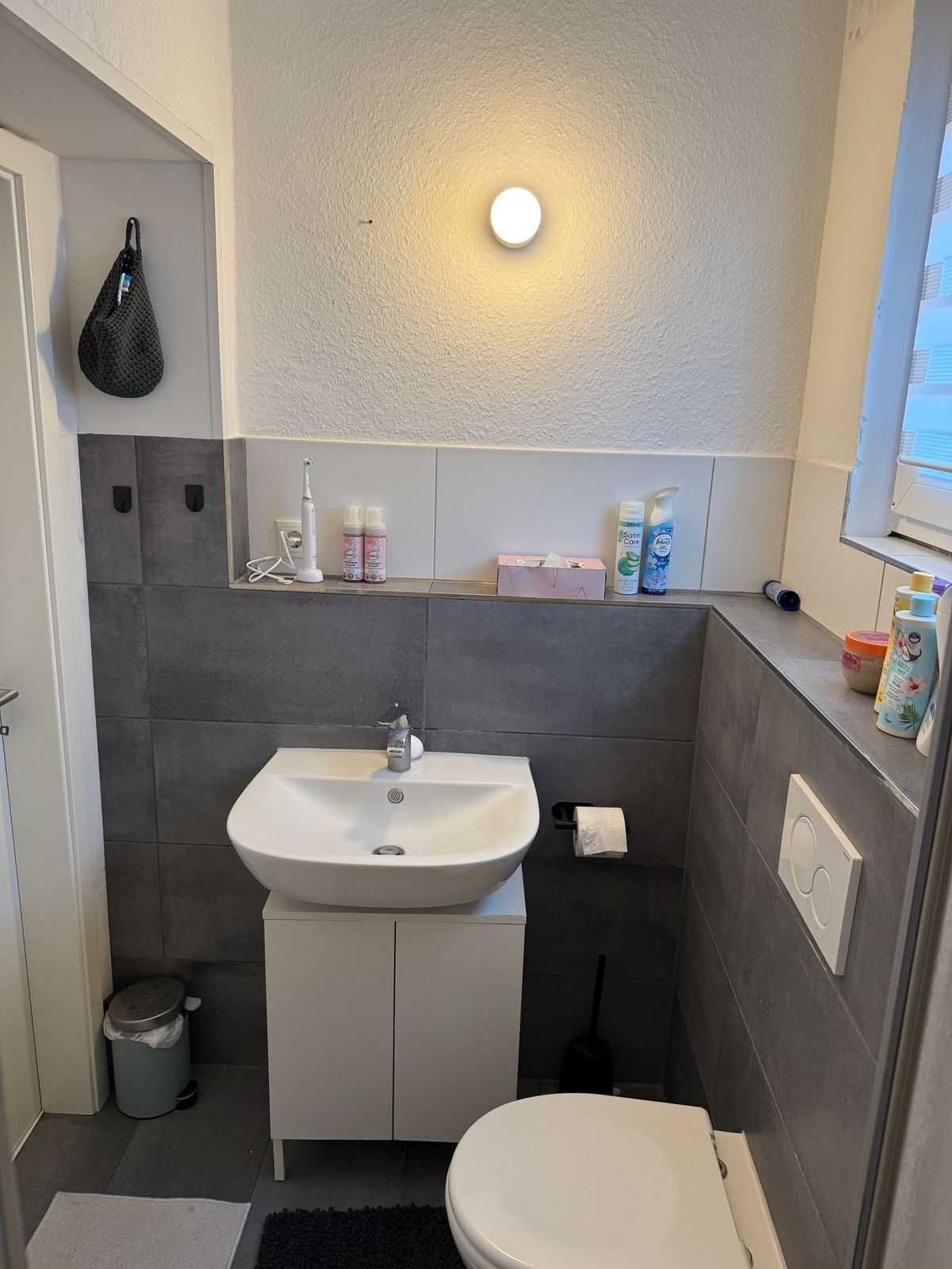 Modernes Bad mit grauen Fliesen, Waschbecken und WC