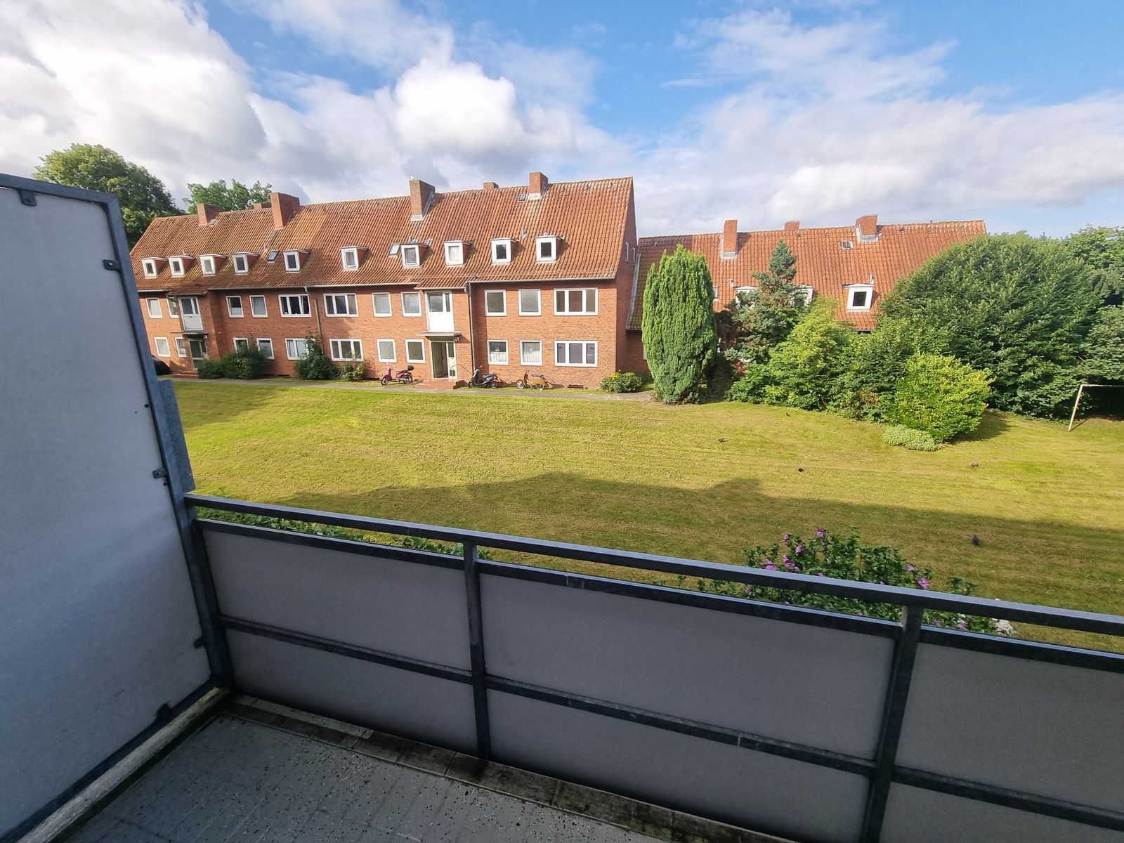 Blick vom Balkon auf Rasenfl&auml;che und Backsteinh&auml;user