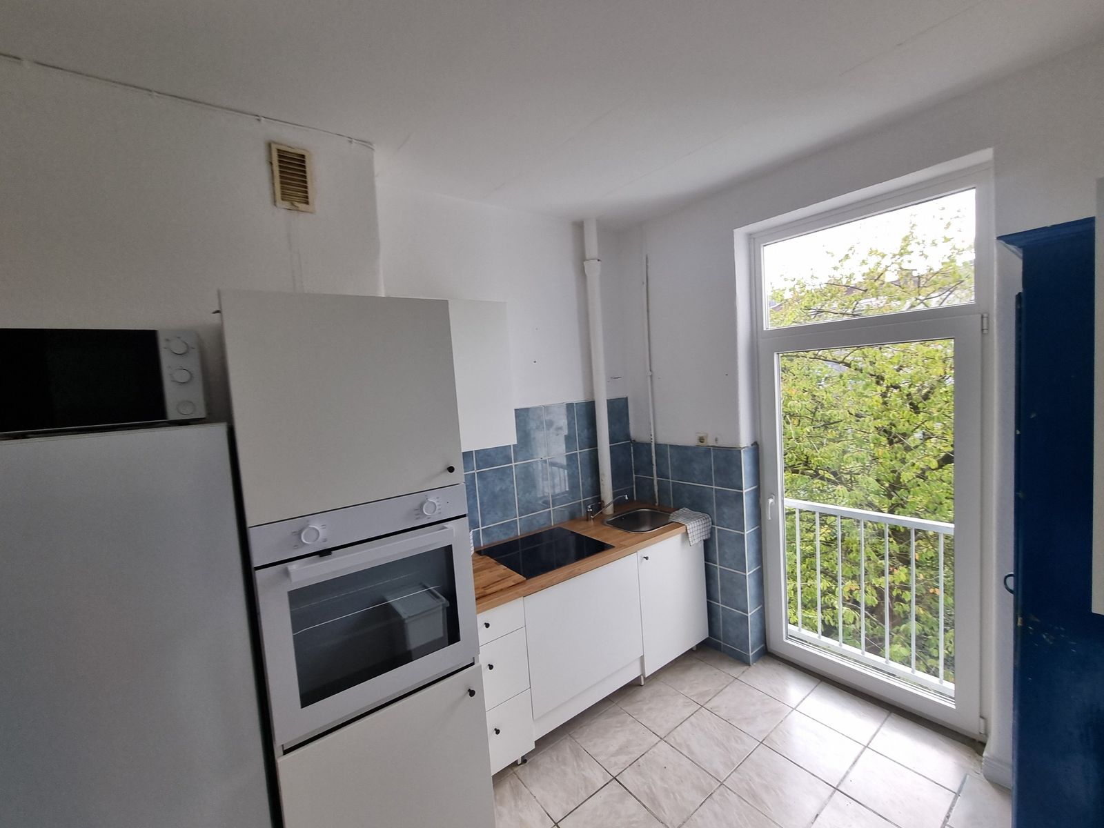 K&uuml;che mit Backofen, Kochfeld, Sp&uuml;le, K&uuml;hlschrank und bodentiefem Fenster