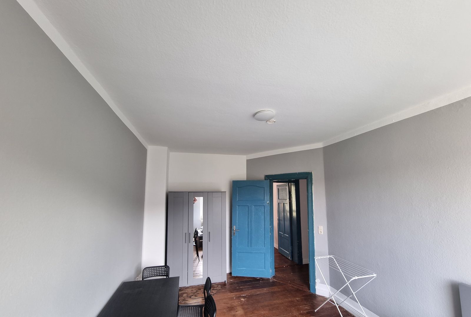 Zimmer mit Kleiderschrank, Tisch und St&uuml;hlen, blaue Altbaut&uuml;r