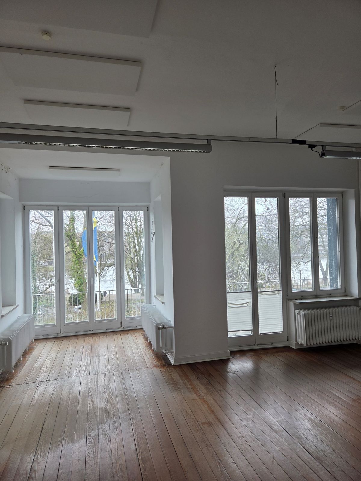 Gro&szlig;er heller Raum mit Holzdielen und bodentiefen Fenstern